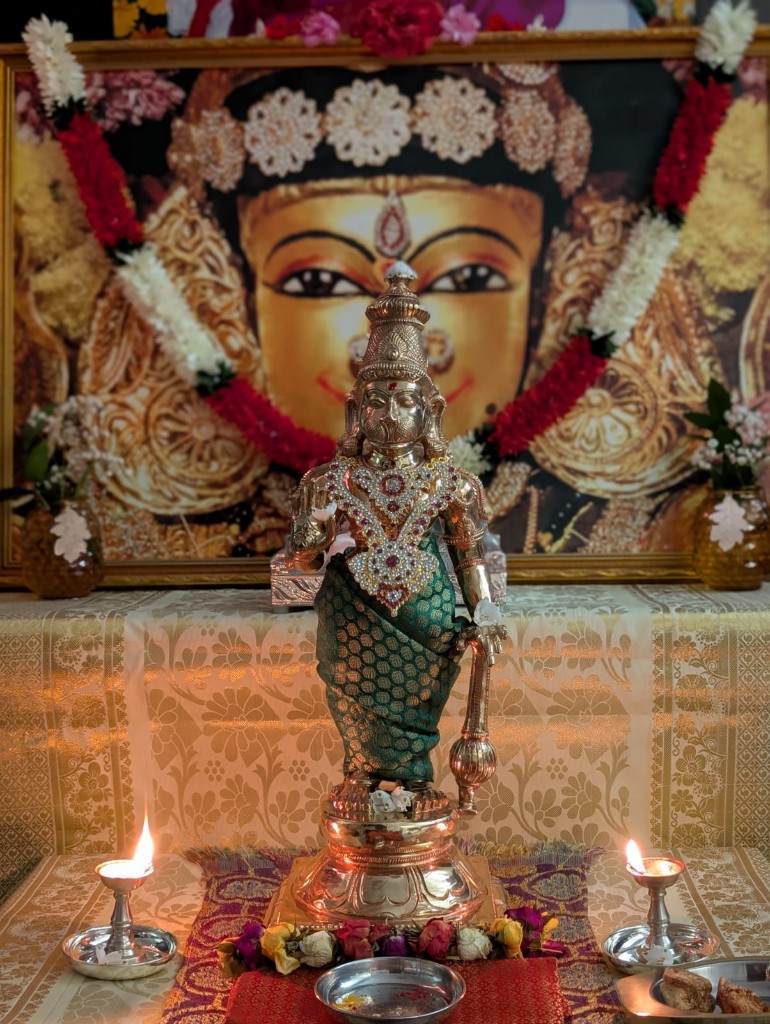 The HRIM Utsav Murthi — a small Hanuman idol adorned in green silk and jewelry.